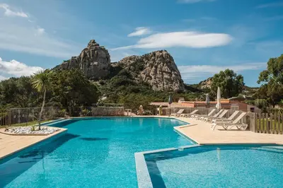 a swimming pool with a mountain in the background at Sapa Di Cala in Bonifacio