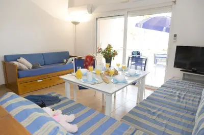 a living room with a table and a blue couch at Résidence Odalys Stella di l'Aria in Tizzano