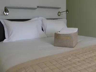 a bed with white pillows and a basket on it at Maison d' Hôtes L'Aria Mezzana in Sainte-Lucie de Porto-Vecchio