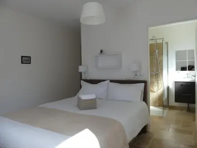 a bedroom with a white bed and a bathroom at Maison d' Hôtes L'Aria Mezzana in Sainte-Lucie de Porto-Vecchio
