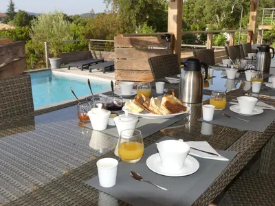 a table with food on it next to a pool at Maison d' Hôtes L'Aria Mezzana in Sainte-Lucie de Porto-Vecchio
