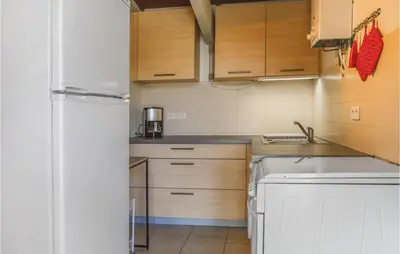 a small kitchen with a refrigerator and a dishwasher at Two-Bedroom Holiday Home In Calcatoggio in Calcatoggio