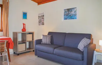 a living room with a blue couch and a table at Two-Bedroom Holiday Home In Calcatoggio in Calcatoggio