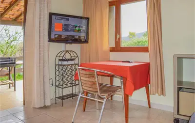 a dining room with a red table and chairs and a television at Two-Bedroom Holiday Home In Calcatoggio in Calcatoggio