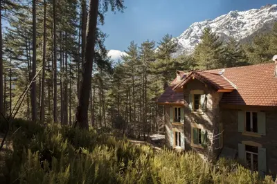 a house in the woods with a mountain in the background at Casa Alta in Vizzavona