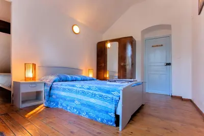 a bedroom with a bed with blue sheets and a mirror at Casa Alta in Vizzavona