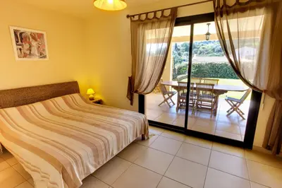 a bedroom with a bed and a balcony with a table at Sci Albellu in Sagone