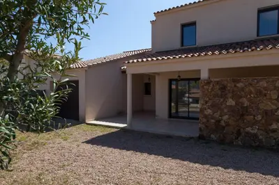 a house with a stone wall in front of it at Sci Albellu in Sagone