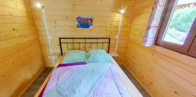 a bed in a log cabin with a window at Funtana a l'Ora in Porto Ota