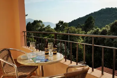 a table and chairs on a balcony with a view at Hotel Stella Marina in Serriera