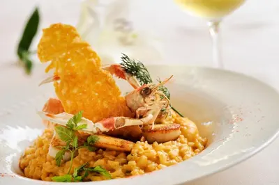 a plate of food with shrimp and corn with a glass of wine at Hotel Stella Marina in Serriera