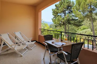 a balcony with a table and chairs and a large window at Hotel Stella Marina in Serriera