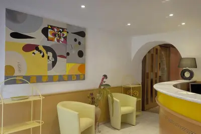 a kitchen with yellow chairs and a painting on the wall at Hotel Stella Marina in Serriera