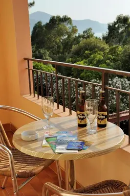 a table with two bottles and glasses on a balcony at Hotel Stella Marina in Serriera