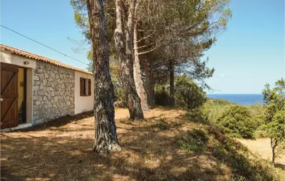 a house with trees and the ocean in the background at Three-Bedroom Holiday Home In Calcatoggio in Calcatoggio
