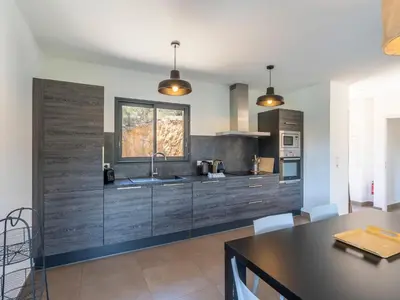 a kitchen with wooden cabinets and a dining table at Holiday Home Bruyères 1 by Interhome in Porticcio