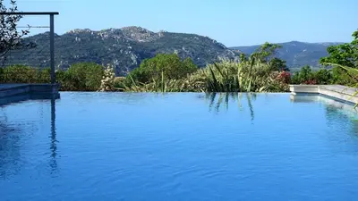 a large pool of water with mountains in the background at Villa Santa Giulia, vue panoramique sur la mer, 900 m de la plage in Porto-Vecchio