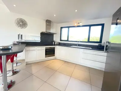 a kitchen with white cabinets and a large window at Villa Santa Giulia, vue panoramique sur la mer, 900 m de la plage in Porto-Vecchio