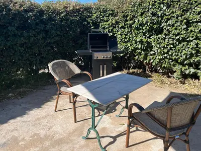 two chairs and a table and a grill with a table and chairs at Bas De Maison in Olivese