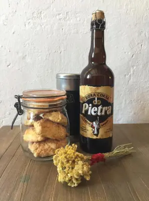 a bottle of beer and some cookies and a jar of flowers at Bas De Maison in Olivese
