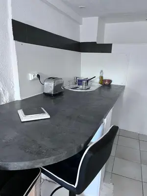 a kitchen with a black counter top and a black chair at Bas De Maison in Olivese