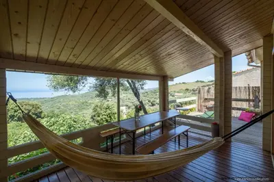 a hammock on the deck of a house with a table at Les Terrasses de Scaglioli in Villanova