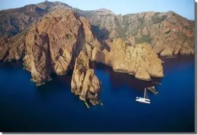 a boat in a large body of water with mountains at Les Terrasses de Scaglioli in Villanova