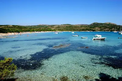 a beach with boats and people in the water at Maison chaleureuse à Bonifacio, 90 m², piscine partagée in Conte