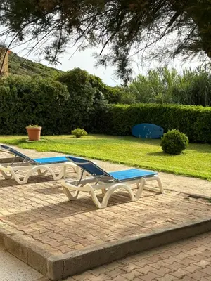 a bedroom with a bed and a chair and a window at Hotel Thalassa in Cargèse