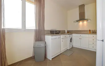 a kitchen with white cabinets and a washer and dryer at Amazing Apartment In Petreto-Biccisano in Petreto-Bicchisano