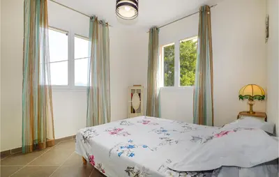 a bedroom with a bed and two windows at Amazing Apartment In Petreto-Biccisano in Petreto-Bicchisano