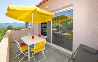 a table with a yellow umbrella on a balcony at Amazing Apartment In Petreto-Biccisano in Petreto-Bicchisano