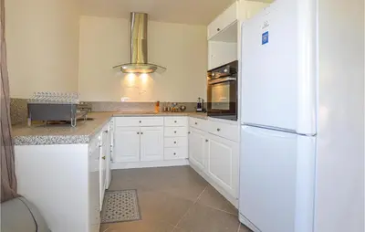 a kitchen with white cabinets and a white refrigerator at Amazing Apartment In Petreto-Biccisano in Petreto-Bicchisano