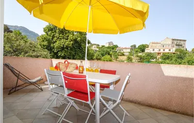 a table and chairs with an umbrella on a patio at Amazing Apartment In Petreto-Biccisano in Petreto-Bicchisano