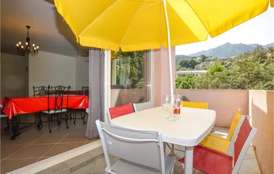 a table and chairs with a yellow umbrella on a balcony at Amazing Apartment In Petreto-Biccisano in Petreto-Bicchisano