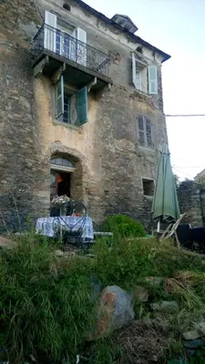 a building with a table and an umbrella in front of it at Appartement 2 chambres A Casa De Giovanni à Pietra-di-Verde en Haute-Corse in Pietra-di-Verde