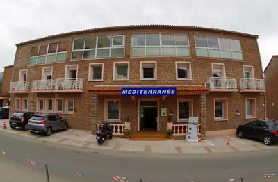 a brick building with a motorcycle parked in front of it at Le Méditerranée in Porto Ota