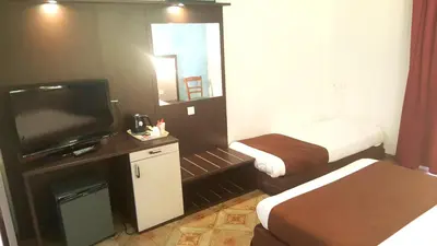 a small hotel room with a bed and a television at Le Méditerranée in Porto Ota