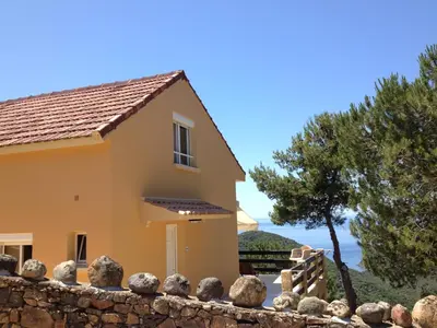 a house with a stone fence and a tree at Villa Romarin in Partinello