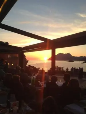 a group of people sitting at tables watching the sunset at Le monte rosso in Porto Ota