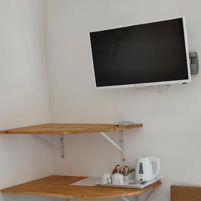 a flat screen tv hanging on a wall with a shelf at Le monte rosso in Porto Ota