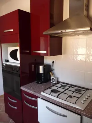 a kitchen with red cabinets and a stove top oven at Corse Villa Porticcio vue Mer in Porticcio
