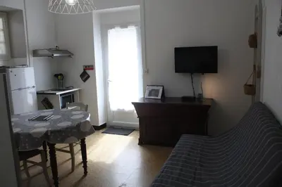 a living room with a table and a kitchen with a television at A CARDICCIA Loc saisonnières PIANA in Piana