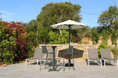 a table and chairs and an umbrella on a patio at Résidence Terre et Mer in Sainte-Lucie de Porto-Vecchio