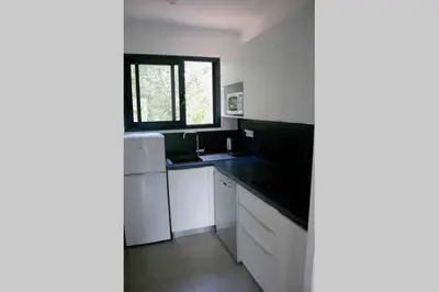 a kitchen with white cabinets and a sink and a window at Résidence Terre et Mer in Sainte-Lucie de Porto-Vecchio