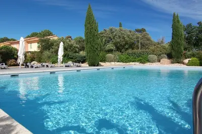 a swimming pool with blue water and white umbrellas at CEDRAT in Porto-Vecchio