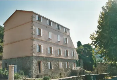 an old stone building on a hill with trees at A Luna Rossa in Coti-Chiavari