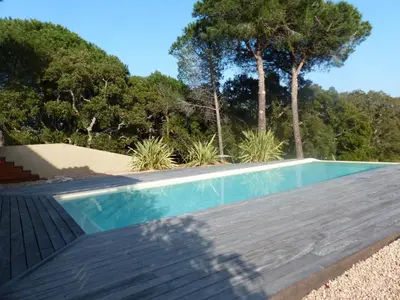 a swimming pool with a wooden deck and trees at Luna verde in Porto-Vecchio