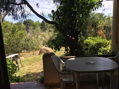 a table and chairs on a porch with a view of a field at Domaine Valdaronu in Sainte-Lucie de Porto-Vecchio