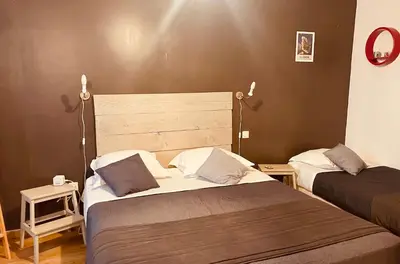 a bedroom with two beds and two lights on the wall at Hôtel U Passa Tempu in Corte